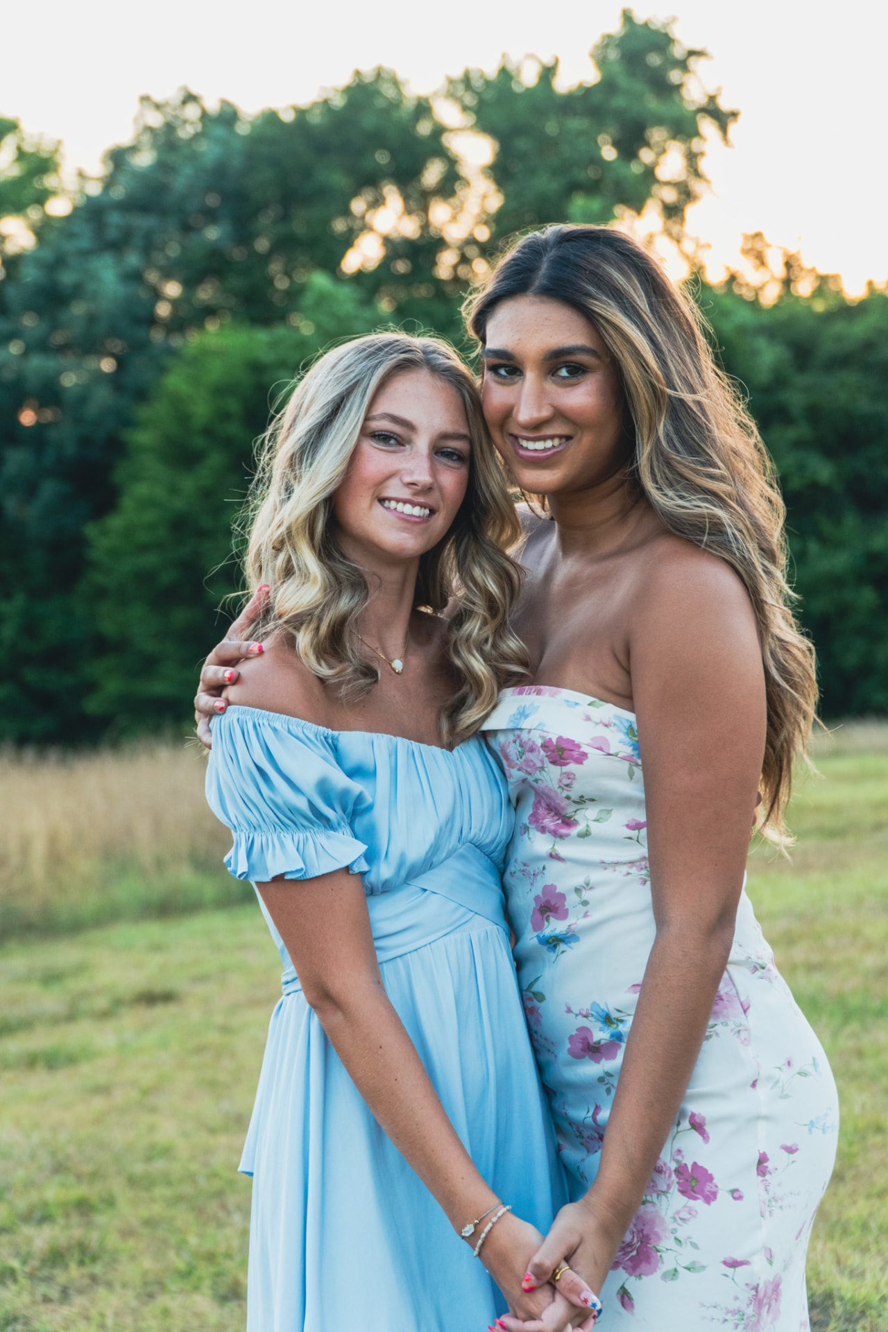 Two friends smiling together at sunset in a field